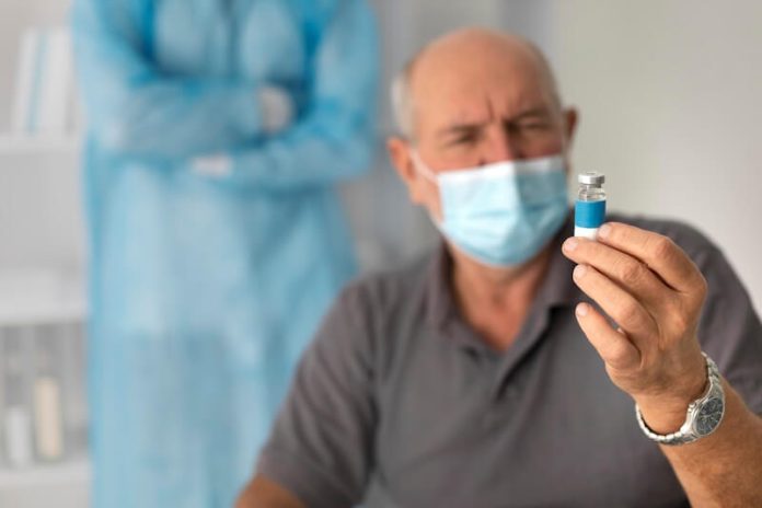 seniors patient age vaccin double vaccination grippe covid 19 peur medecin pharmacien ma sante Un patient âgé regarde avec méfiance un vaccin contre le covid ou la grippe.