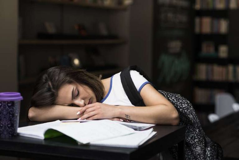 Une adolescente endormie sur son bureau, épuisée par un début de cours trop matinal.