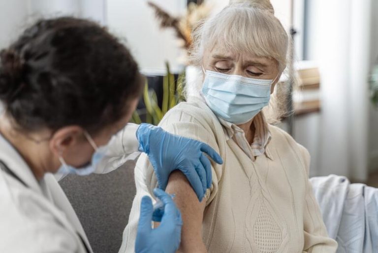 Une personne âgée qui se fait vacciner contre la grippe, tout en gardant une certaine appréhension sur son efficacité.