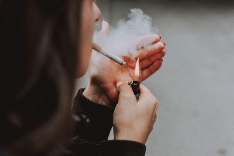 Une jeune femme qui fume une cigarette en France parce que ce n'est pas interdit.