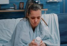 Une femme qui a du mal à dormir et qui hésite à prendre de la mélatonine en gélule.