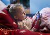 Parentalité : comment protéger son enfant des écrans ? Une enfant les yeux rivés sur le téléphone d'un de ses parents.