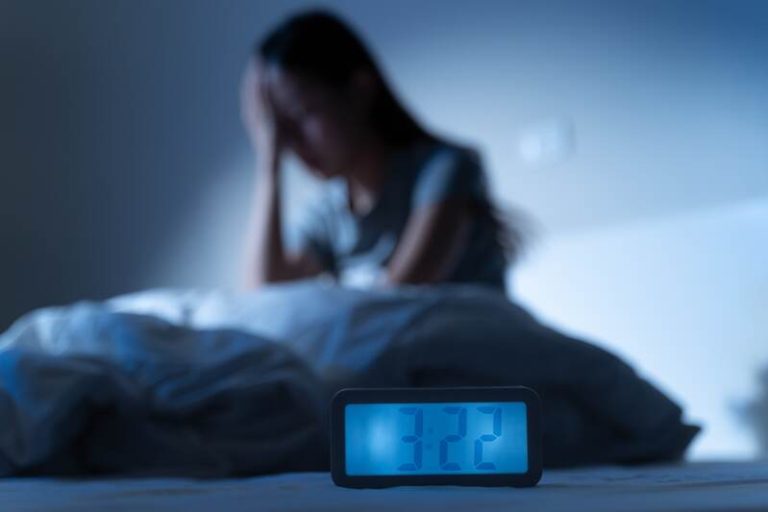 Une femme en pleine nuit blanche qui se demande si elle va pouvoir rattraper les heures de sommeil perdues.