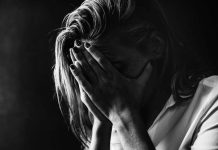 Une femme qui se prend la tête dans les mains, rongée par l'anxiété.