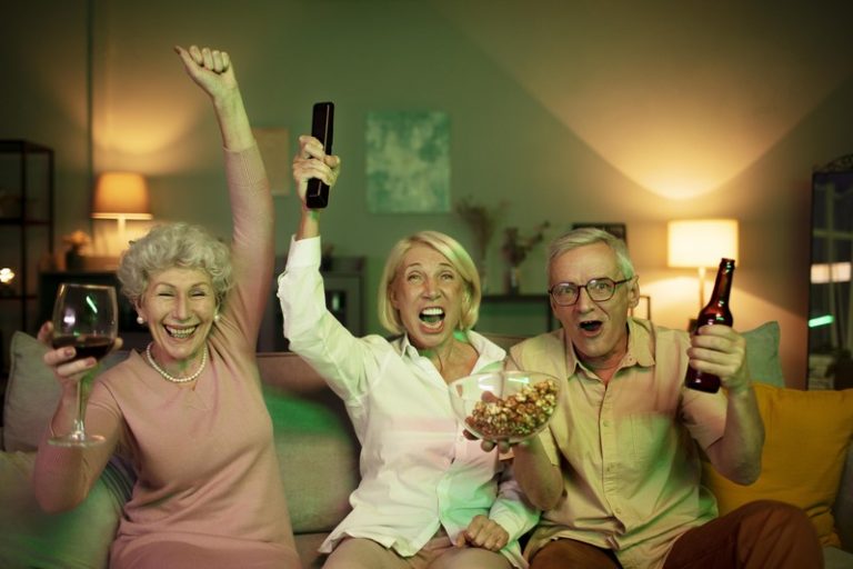 Une bande de copains baby boomers devant la télévision avec de l'alcool.
