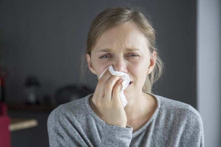 Une femme qui cherche une solution pour déboucher son nez pendant l'hiver.