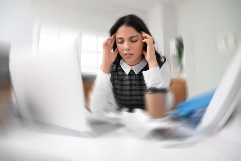 Une femme derrière son bureau qui souffre de fatigue mentale.