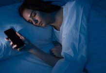 Quand lāapnĆ©e du sommeil se dĆ©piste sur smartphone Une femme qui dort avec son tĆ©lĆ©phone pour dĆ©tecter les symptĆ“mes d'une apnĆ©e du sommeil.