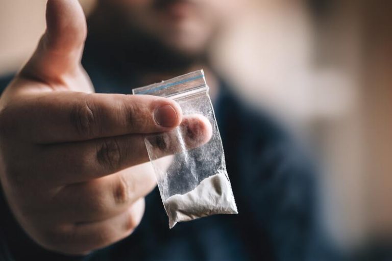 Un homme qui tient un sachet de cocaïne dans sa main.