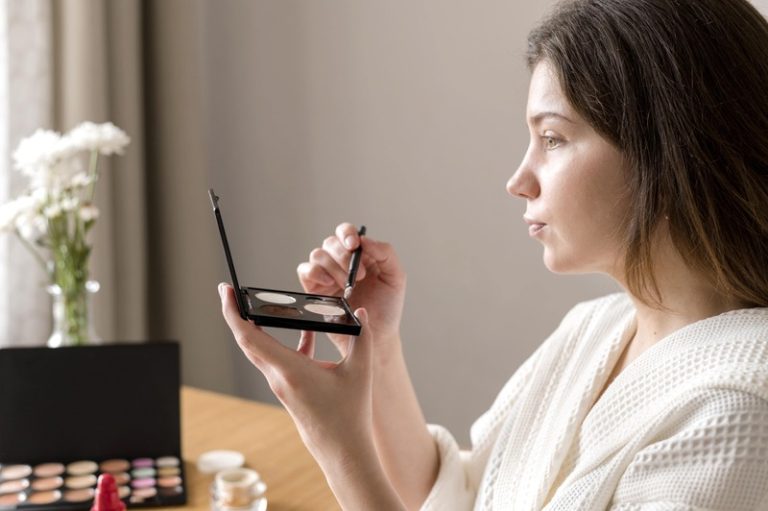Une femme qui se maquille avec des cosmétiques pailletés toxiques, contaminés au titane.