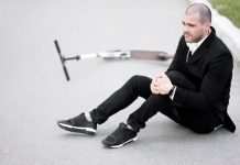 Ligament croisé : une rupture sans douleurs est-elle possible ? Un homme freinant en trottinette qui bloque son pied sur le sol, provoquant une torsion brutale du genou qui a rompu le ligament.