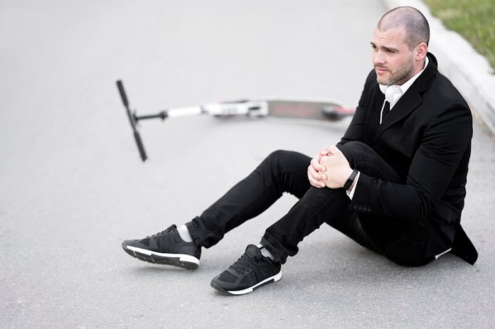 Ligament croise anterieur symptômes ma sante Un homme freinant en trottinette qui bloque son pied sur le sol, provoquant une torsion brutale du genou qui a rompu le ligament.