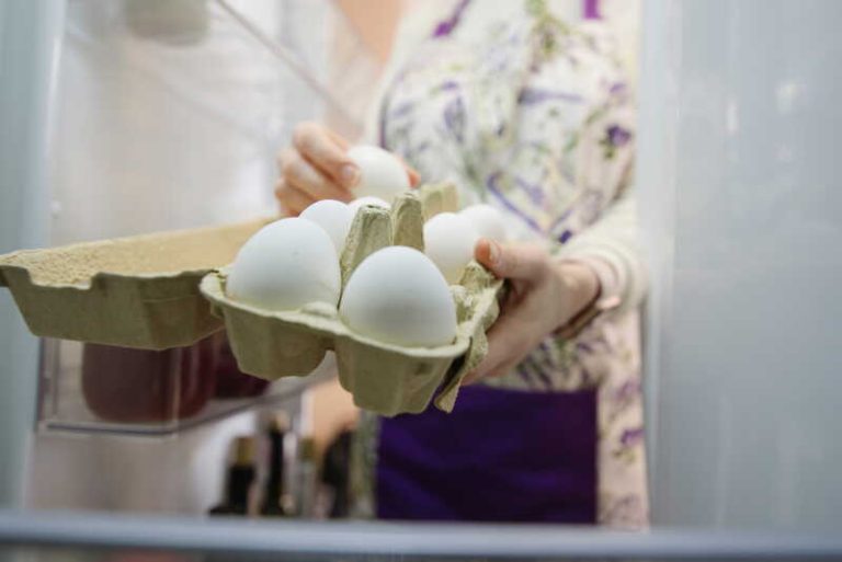 Une femme qui cherche des oeufs dans son réfrigérateur.