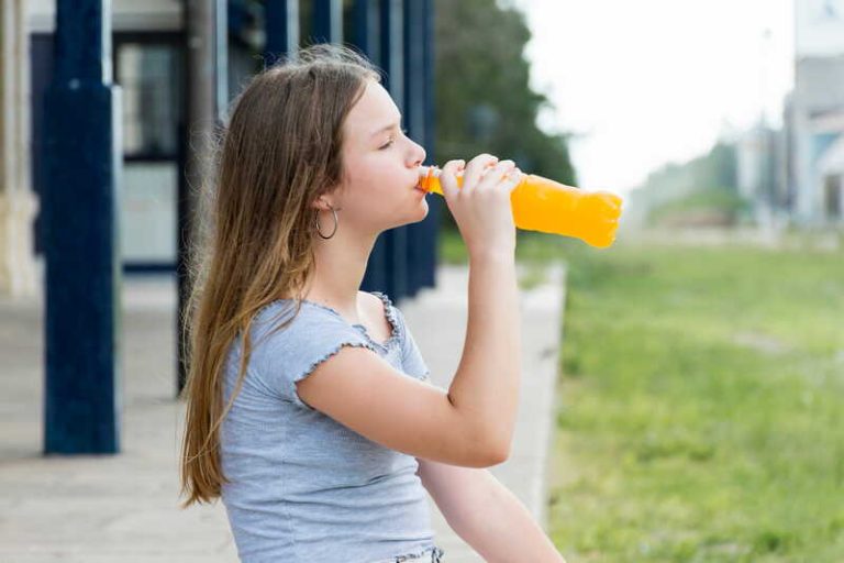 Une jeune adolescente qui boit une boisson sucrée.