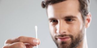 Oreilles : pourquoi faut-il sérieusement se méfier du coton-tige ? Un homme qui s’apprête à se nettoyer les oreilles avec un coton-tige classique.