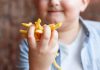 Obésité infantile : l’éducation alimentaire à l’école peut-elle ralentir l’épidémie ? Un enfant en situation d’obésité tenant des frites dans les mains, faute d’avoir été sensibilisé au bien manger.