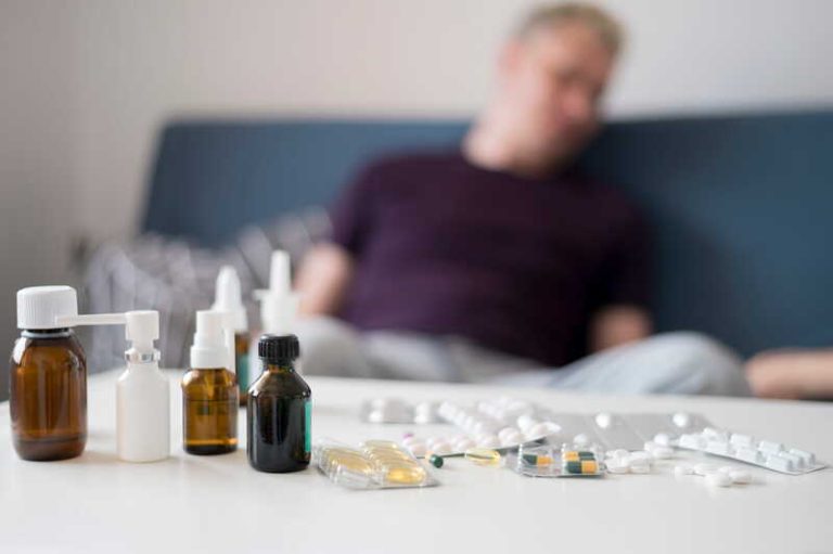Un homme enrhumé qui tente de se soigner avec des médicaments inutiles, tels que du sirop pour la toux ou des sprays nasaux.