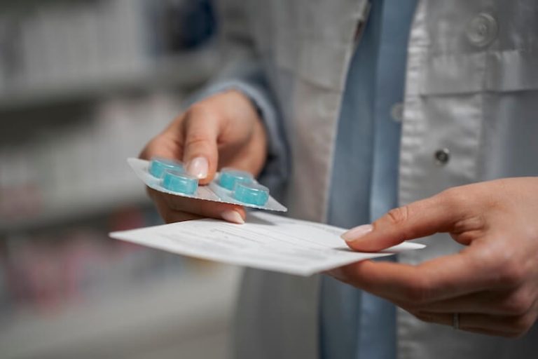 Une pharmacienne s’apprête à délivrer un médicament à un patient et consulte la notice afin de vérifier les effets secondaires et s’assurer que ce traitement lui convient.