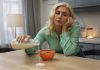 Fatigue saisonnière : quels aliments privilégier pour retrouver votre énergie ? Une femme épuisée, distraite par la fatigue au point de renverser son lait sur la table, illustre le manque de respect des quatre piliers alimentaires essentiels pour relancer l’énergie.
