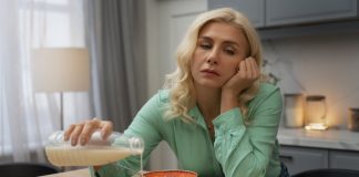 Fatigue saisonnière : quels aliments privilégier pour retrouver votre énergie ? Une femme épuisée, distraite par la fatigue au point de renverser son lait sur la table, illustre le manque de respect des quatre piliers alimentaires essentiels pour relancer l’énergie.