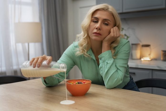 fatigue hivernal alimentation energie ma sante Une femme épuisée, distraite par la fatigue au point de renverser son lait sur la table, illustre le manque de respect des quatre piliers alimentaires essentiels pour relancer l’énergie.
