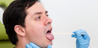 Laryngite : comment soulager rapidement une perte de voix ? Un homme en train de faire examiner sa gorge par un médecin, car il suspecte une laryngite.