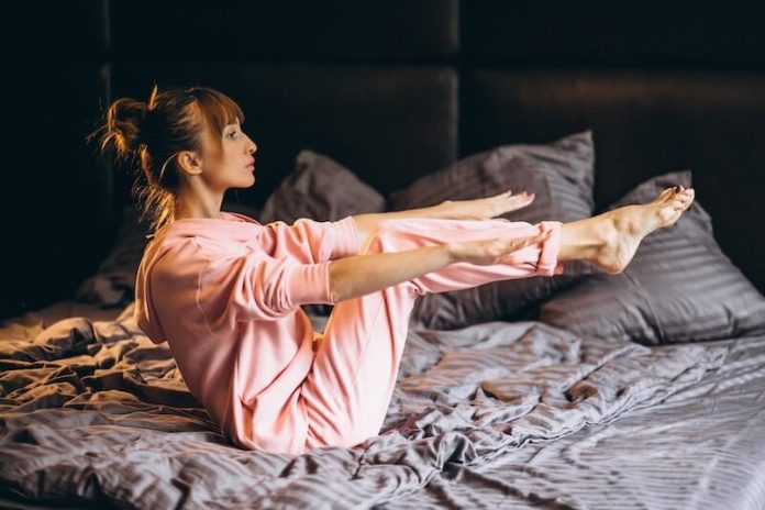 sport dormir bienfaits ma sante Une femme pratiquant une séance d'abdominaux avant de se coucher.