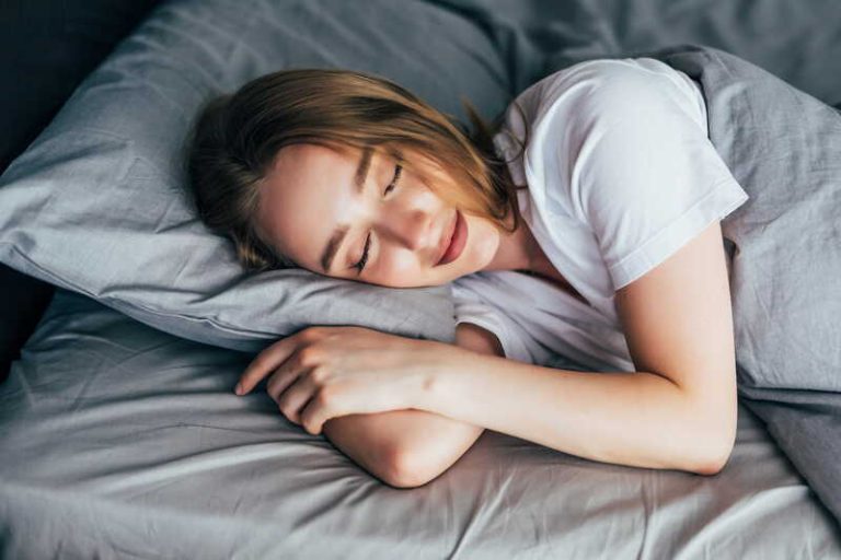Une femme qui se couche après avoir accompli sa routine du soir pour être plus heureuse.