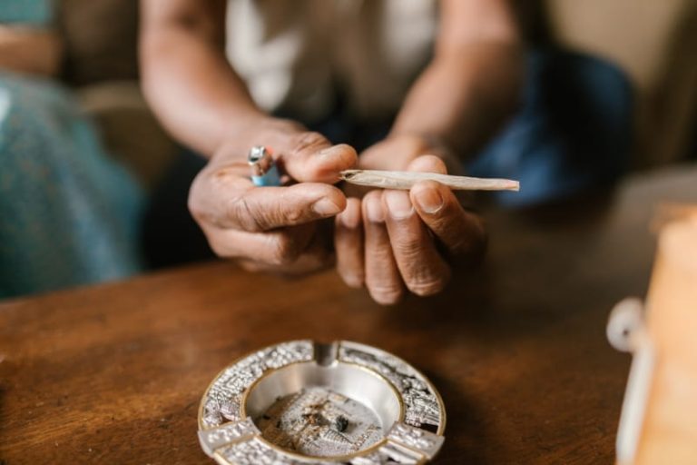 Un jeune homme qui roule et fume un joint de cannabis.