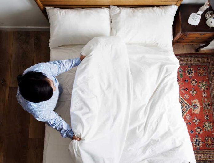 Hygiène du quotidien à quelle fréquence faut-il vraiment laver ses draps Ma Santé Un homme qui vient de changer ses draps pour laver sa housse de couette, son drap-housse et ses taies d’oreiller.