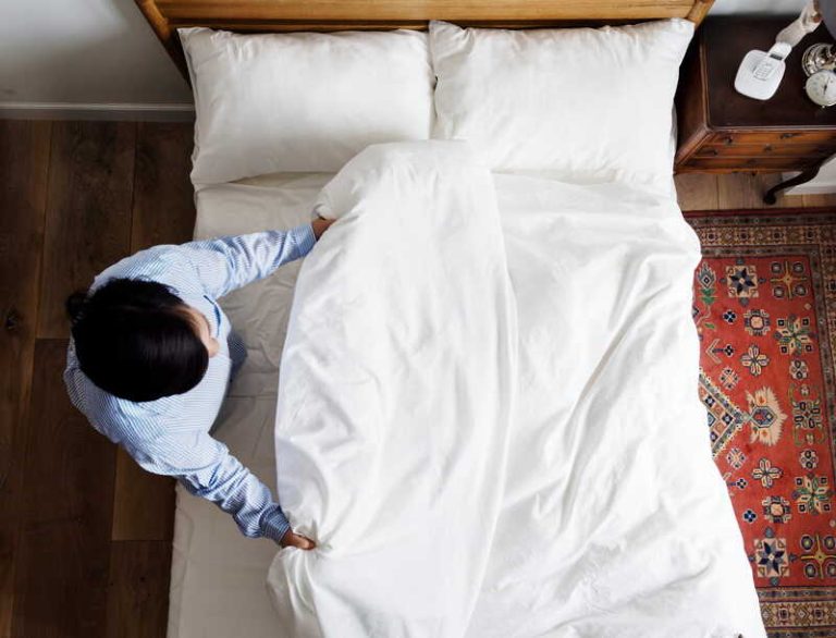 Un homme qui vient de changer ses draps pour laver sa housse de couette, son drap-housse et ses taies d’oreiller.