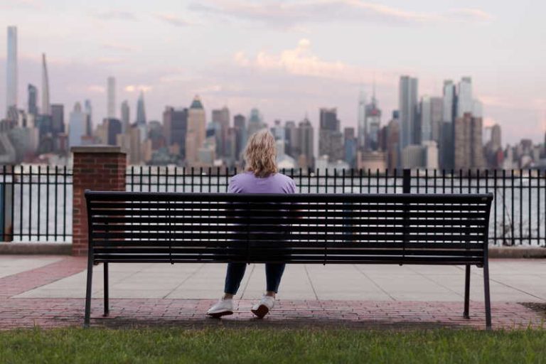 Une femme de quarante ans se posant des questions existentielles, assise sur un banc.