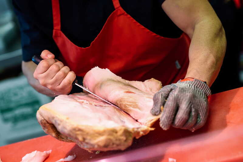 Un charcutier tranche une pièce de charcuterie contaminée par la bactérie Listeria.