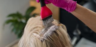 Colorations pour cheveux : faut-il s’inquiéter des produits de supermarché ? Une femme qui réalise une coloration à la maison avec des produits de supermarché.