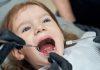 Poussée dentaire du bébé : que faire pour apaiser la douleur ? Une petite fille consulte le dentiste car elle ressent une douleur à la mâchoire, possiblement liée à une poussée dentaire.