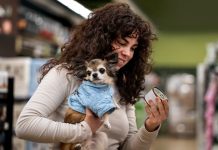 Alimentation des chiens et des chats : gare aux fausses promesses ! Une femme achète de la nourriture pour son chien sans se méfier des fausses promesses alimentaires.