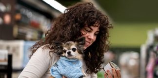 Alimentation des chiens et des chats : gare aux fausses promesses ! Une femme achète de la nourriture pour son chien sans se méfier des fausses promesses alimentaires.