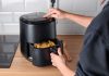 Une jeune femme qui utilise un Airfryer pour cuisiner plus sainement.