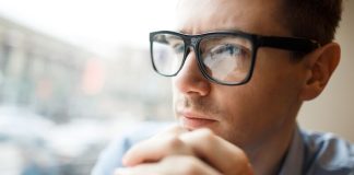 Troubles de la vision : comment savoir si je suis astigmate ? Un homme qui porte des lunettes avec des verres toriques, destinés à corriger son astigmatisme.