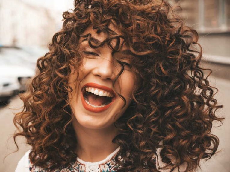 Une femme aux beaux cheveux bouclés qui adopte une routine simple et rapide pour en prendre soin.