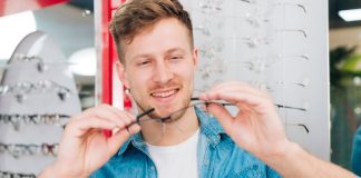Lunettes : comment bien choisir sa monture selon la forme de son visage ? Un homme essaie des lunettes adaptées à la forme de son visage, avec les conseils d’un opticien.