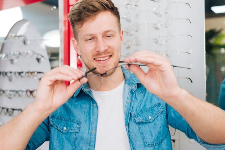 Un homme essaie des lunettes adaptées à la forme de son visage, avec les conseils d’un opticien.