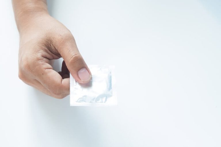 La main d’un homme tient un préservatif encore emballé. Une image qui illustre la contraception masculine et la protection contre les grossesses et les infections sexuellement transmissibles.