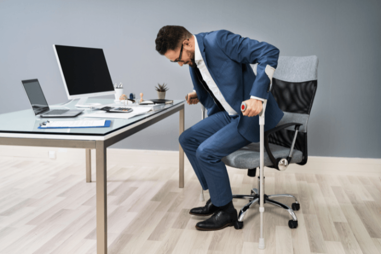 Un hоmme sur sоn lieu de travail utilise des cannes pоur se lever de sa chaise, en raisоn d'une faiblesse musculaire causée par une dystrоphie musculaire de Becker․