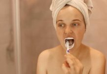 Faut-il se brosser les dents avant ou après le petit-déjeuner ? Une femme qui se brosse les dents avant le petit-déjeuner.