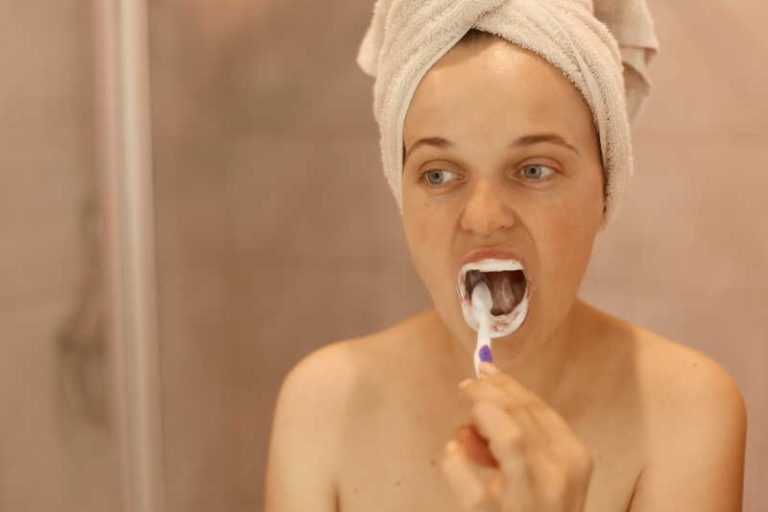 Une femme qui se brosse les dents avant le petit-déjeuner.