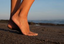 Pourquoi n’avons-nous pas tous la même forme de pied ? Pied d’une personne sur une plage de sable, dont l’empreinte reflète la forme du pied ainsi que l’équilibre et la répartition des pressions lors de la marche.
