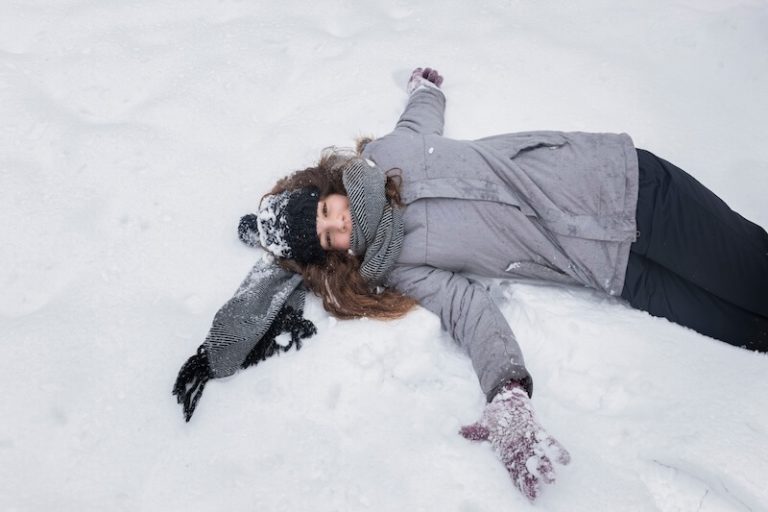 Une personne allongée dans la neige, immobile et inconsciente, avec un risque d’hypothermie.
