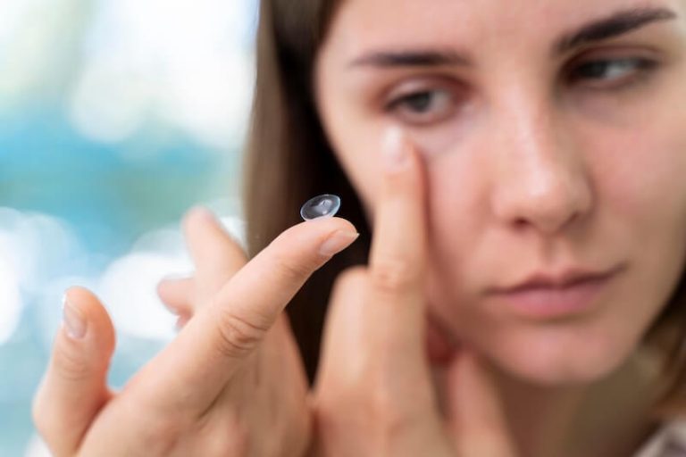 Une femme appliquant ses lentilles de contact, atteinte d’un trouble oculaire.