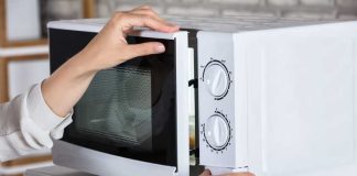 Une femme qui réchauffe son plat surgelé industriel au micro-ondes.